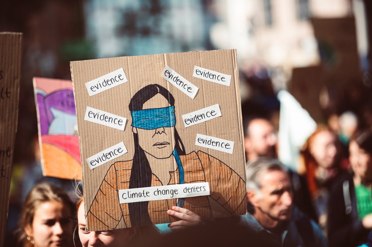 A vibrant protest scene with a focus on a creative sign about climate change denial.