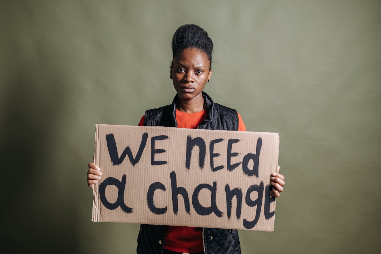 Portrait of an activist with a placard stating 'We need a change', highlighting human rights.